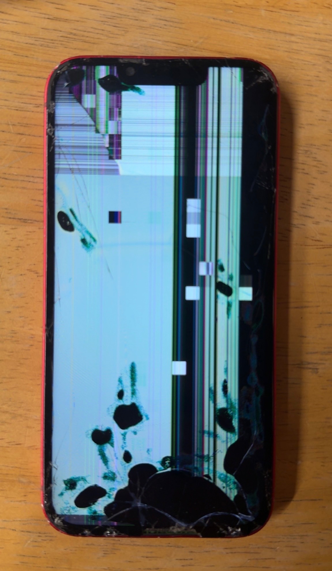 Red iPhone with severe display glitch and shattered screen